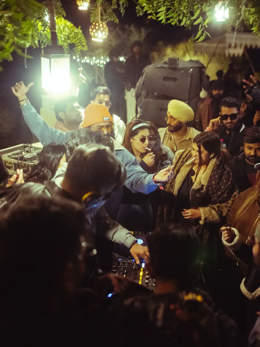 Crowd dancing under lanterns and trees at night