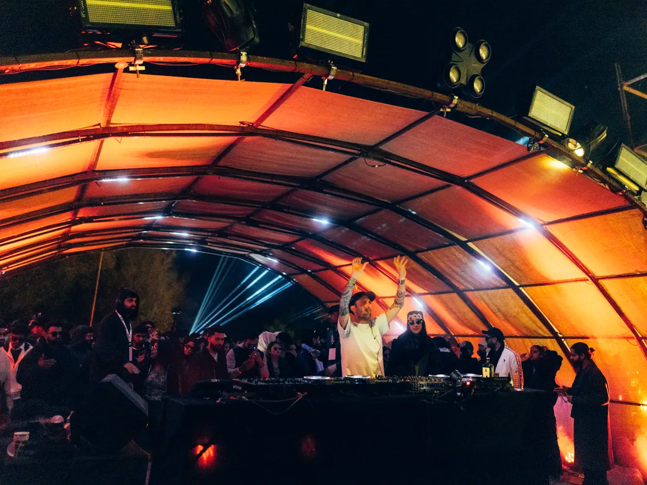 The arch stage lit in deep red above a full dancefloor
